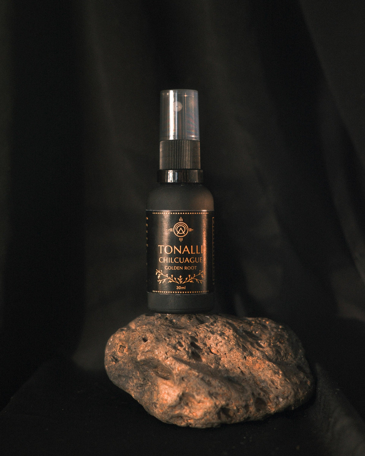 Tonalli Chilcuague Golden Root oral spray standing on volcanic stone against a black backdrop